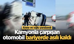 Kamyonla çarpışan otomobil bariyerde asılı kaldı: Anne ve oğlu yaralandı